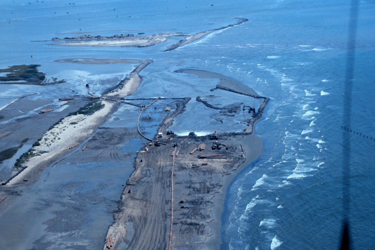 An aerial view of construction dredge pipes depositing sediment into containmentareas of the restoration site to build marsh platform