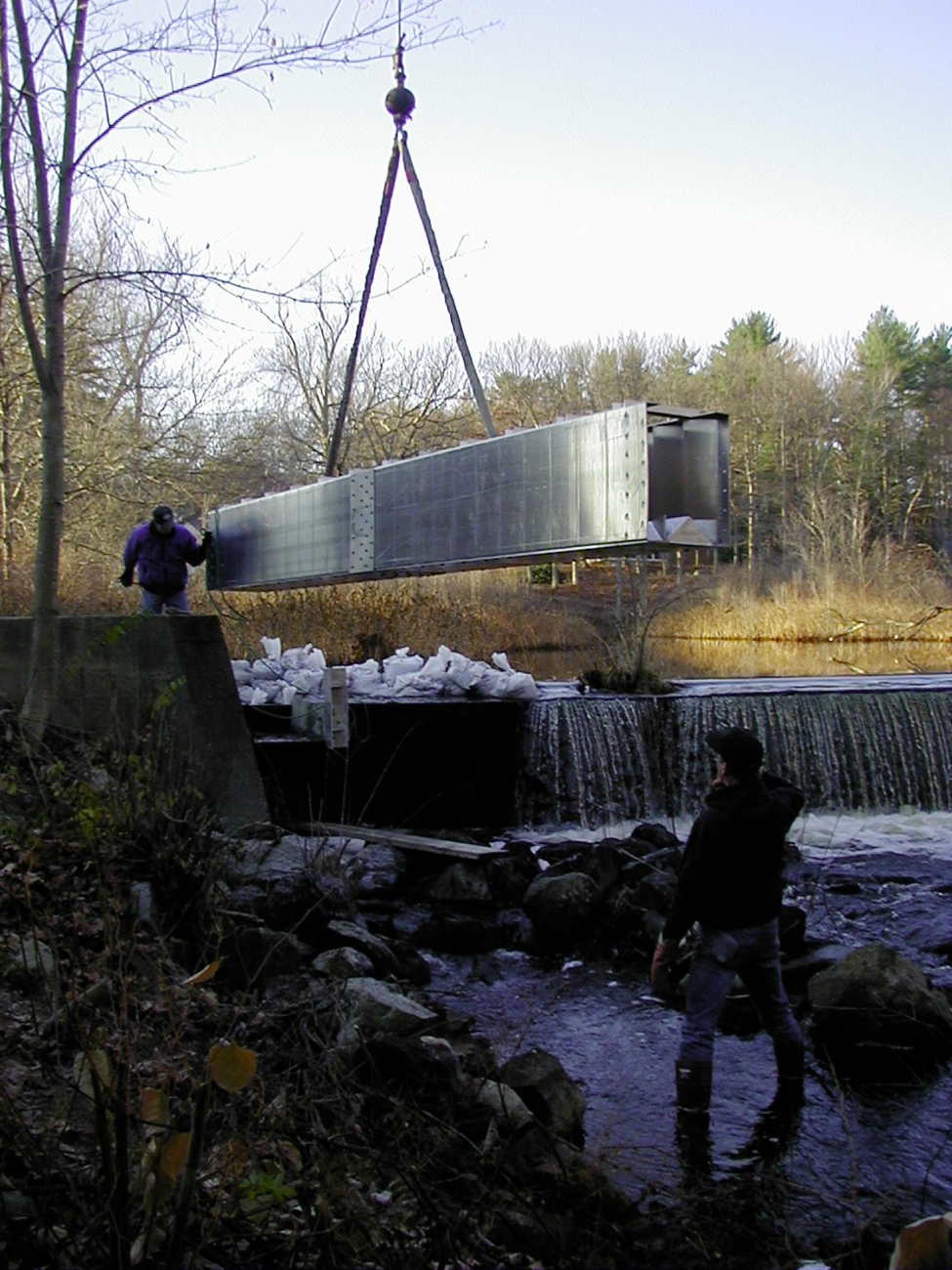 The crane lowers the first section into place, it is just about to be droppedinto the notched dam