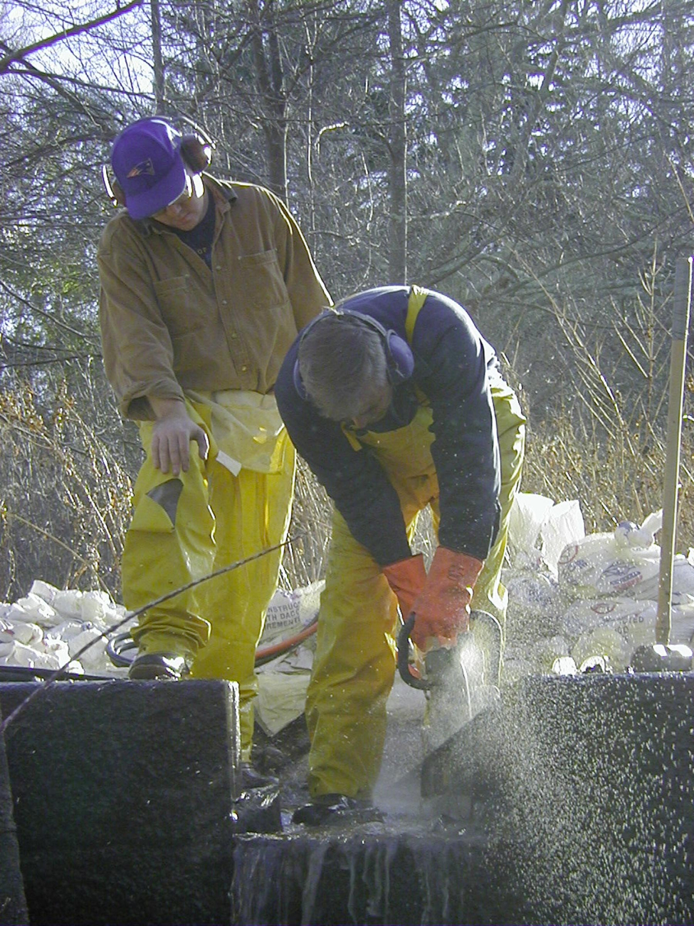 A close up of two workers notching the dam