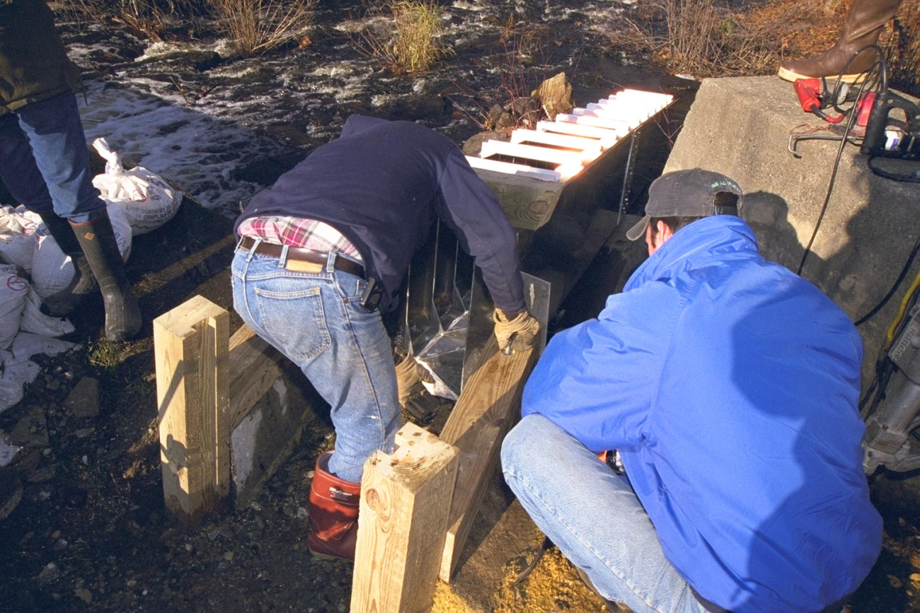 Contractors begin to fit the fish ladder into the notch in the dam