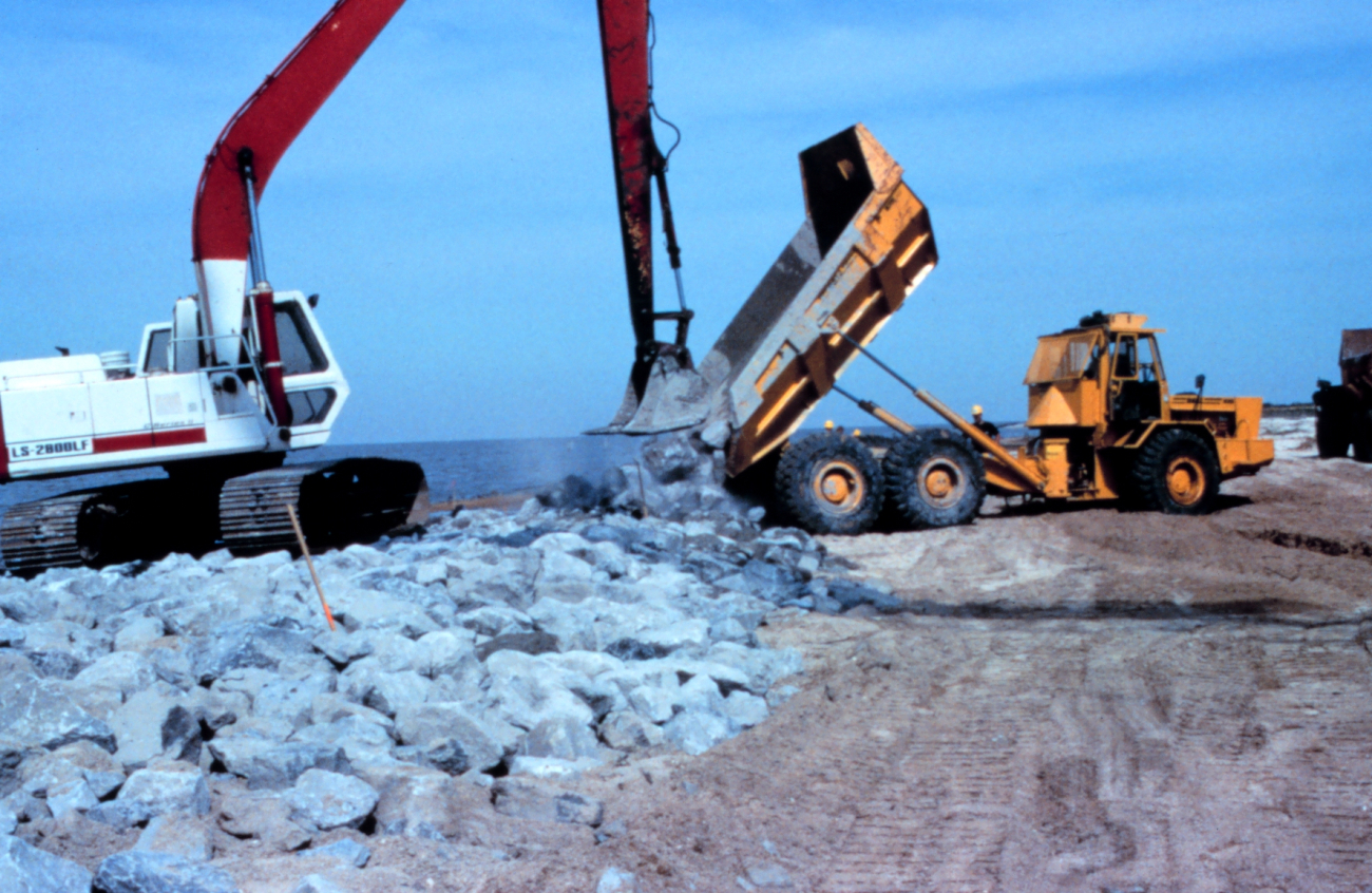 A large crane places rock in the dump truck at the construction site