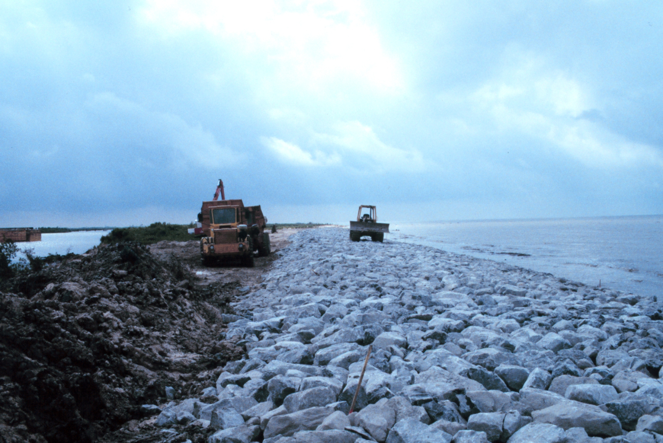 A view of the rock armored beach with construction equipment in thebackground