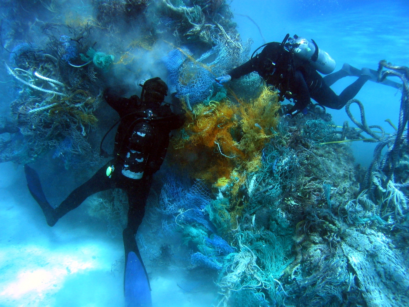 Scuba divers removing derelict net from reef