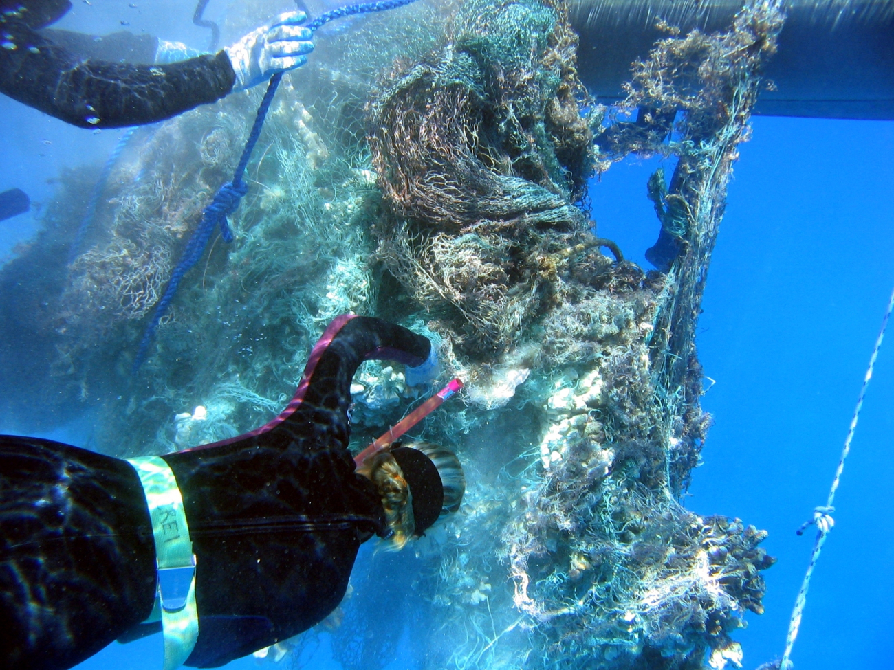 Cutting out heavy reef substrate material from derelict net prior to liftingonto inflatable boat for transport to CASITAS