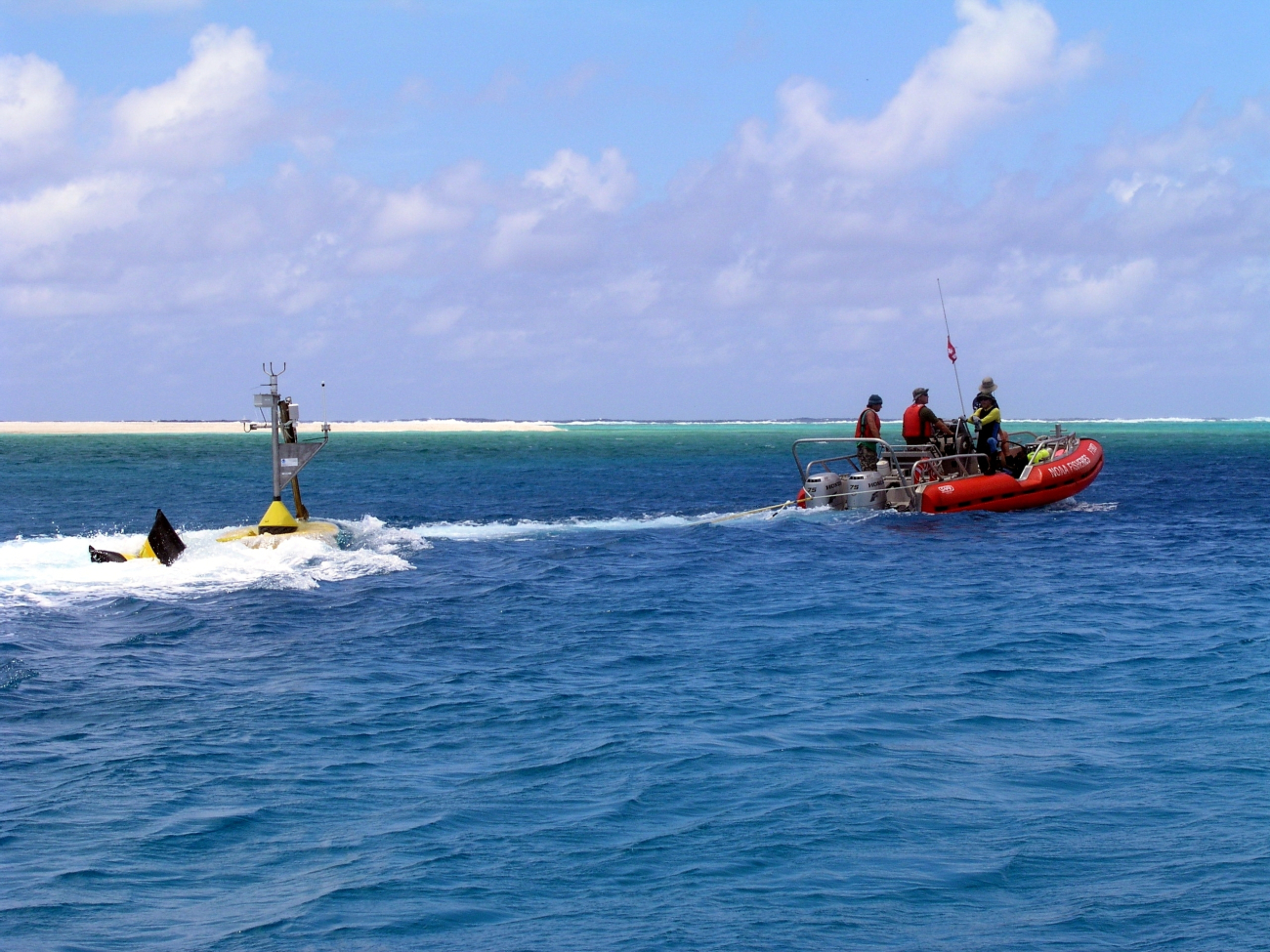 Oceanographers tow a CREWS buoy through a channel for deployment inside an atoll
