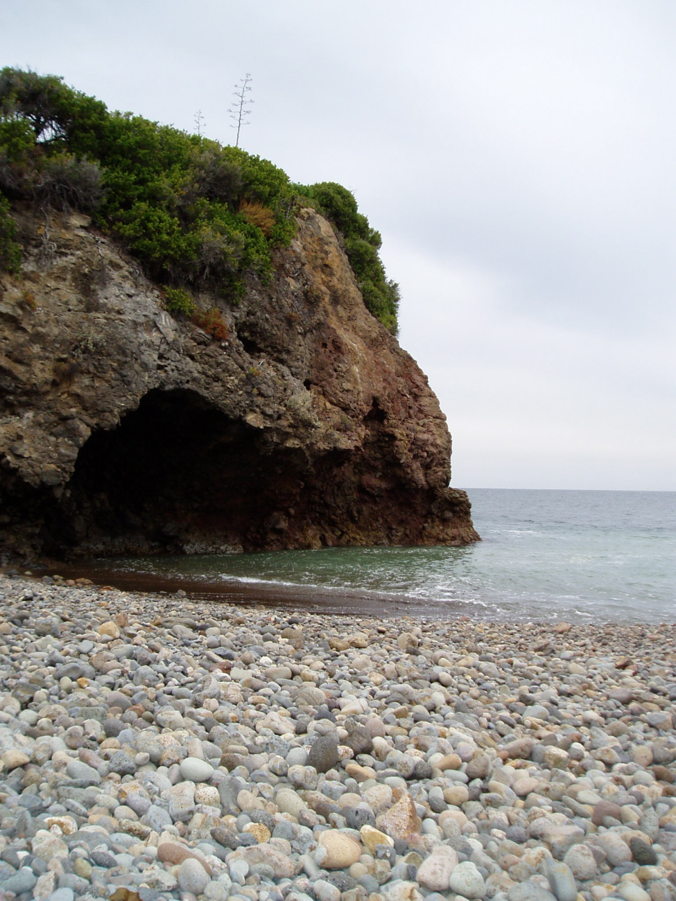 Beginnings of a sea cave or possibly an arch with a boulder beach in theforeground