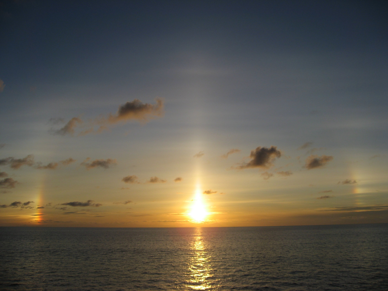 Sunset at sea with sun dogs on each side of the setting sun