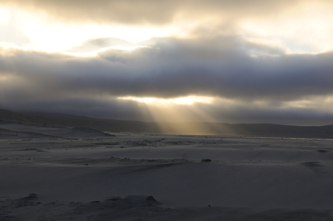 Sunbeams  peaking through a hole in the clouds and over a lonely beachon Santa Rosa Island