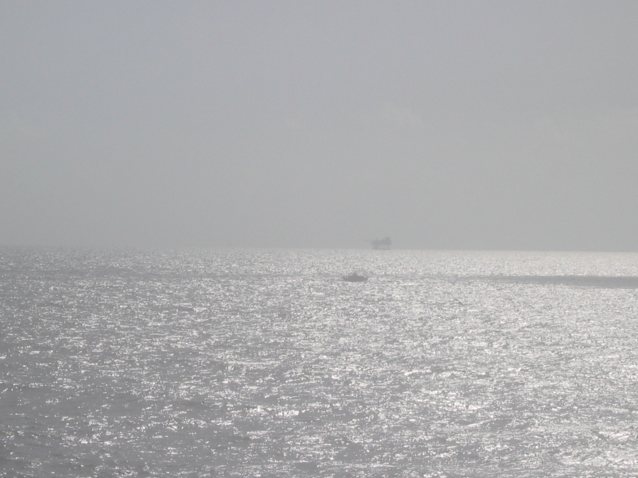 Survey launch and oil platform on a hazy day