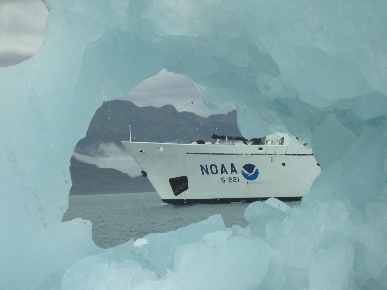 Bow of the NOAA Ship RAINIER as seen through a hole in a melting ice berg