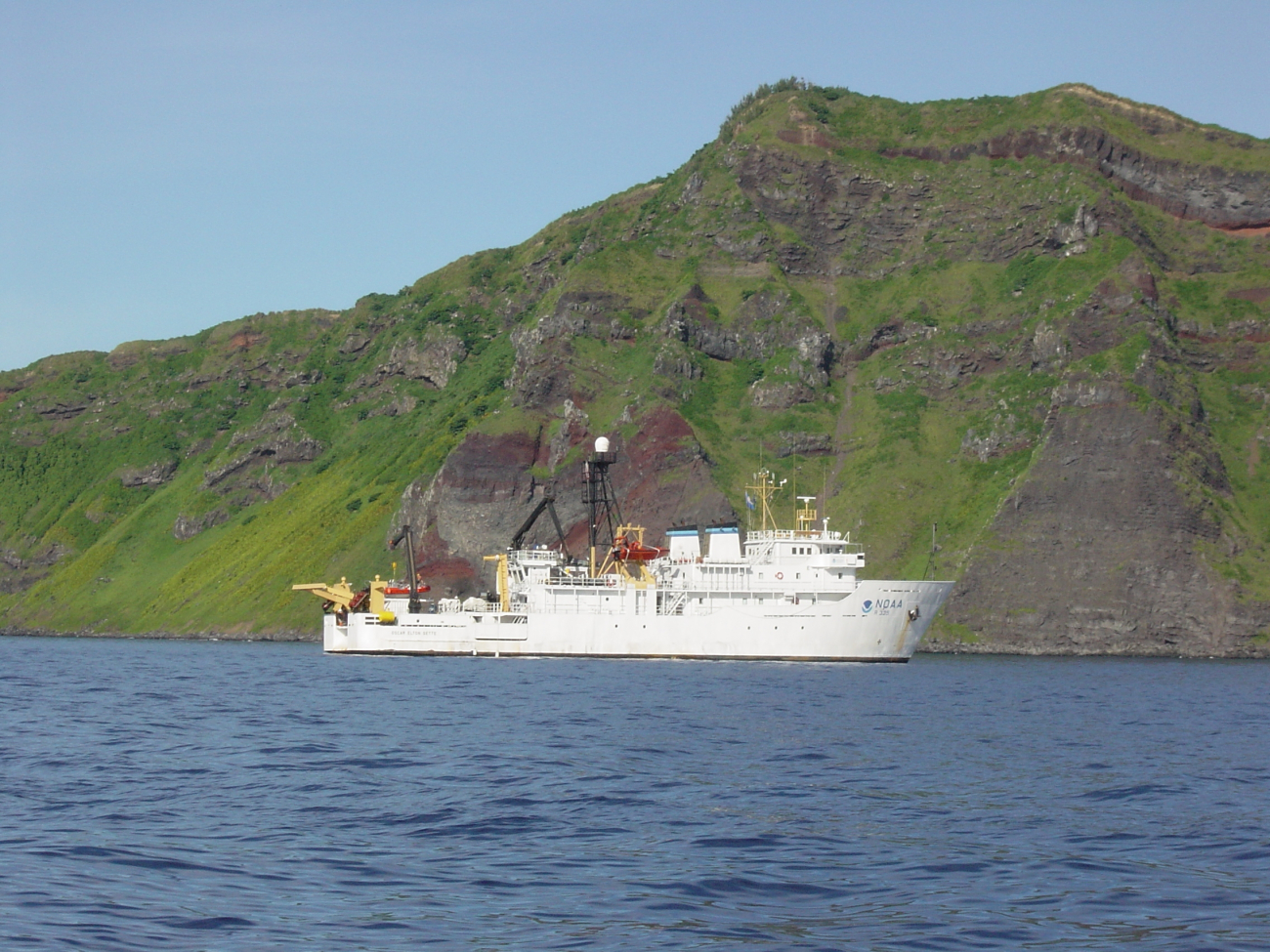 NOAA Ship OSCAR ELTON SETTE at anchor off a volcanic island