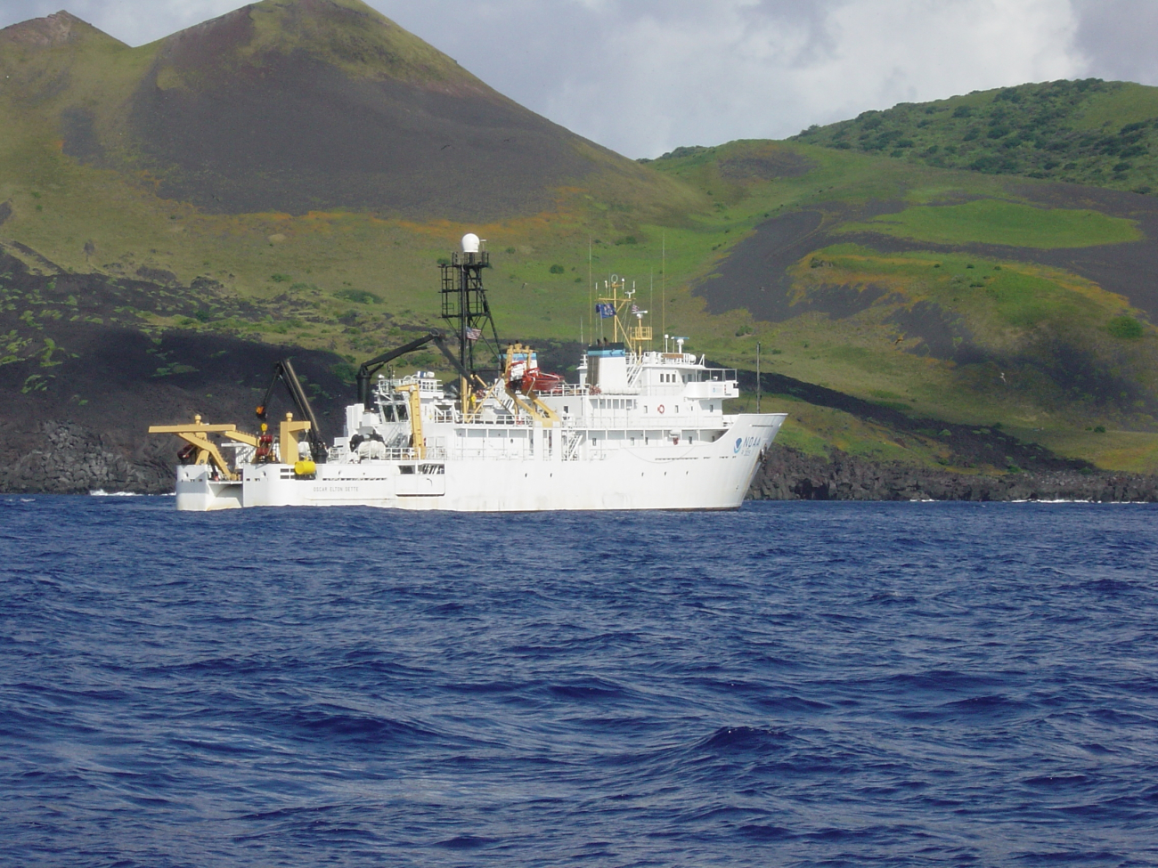 NOAA Ship OSCAR ELTON SETTE at anchor off a volcanic island