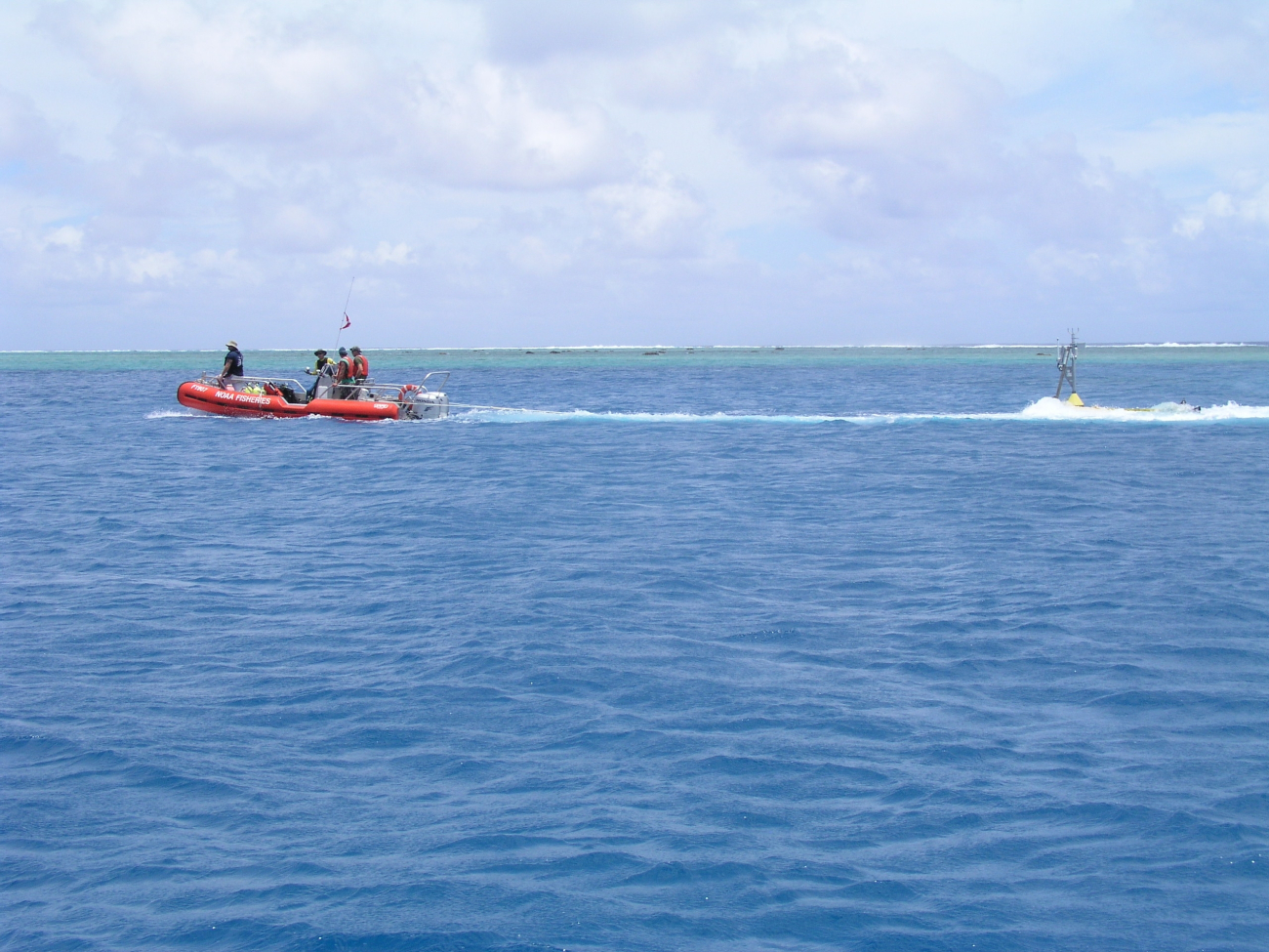 Oceanographers tow a CREWS buoy through a channel for deploymentinside of an atoll lagoon