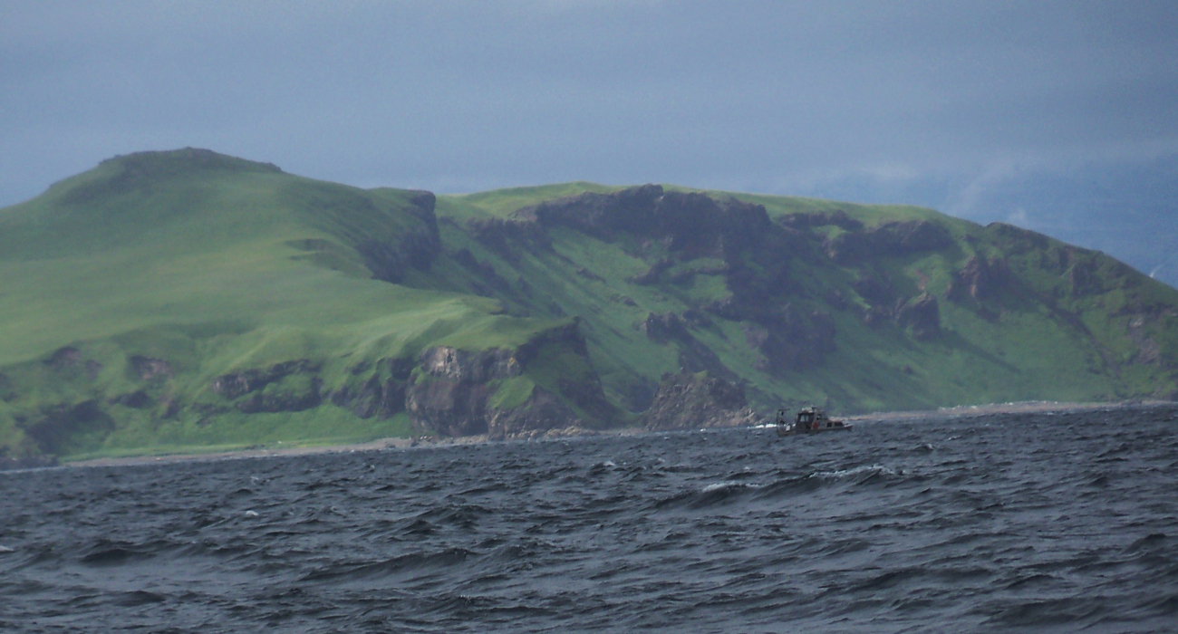 A NOAA Ship RAINIER survey launch seen against the backdrop of the verdanthills of the Pavlof Islands
