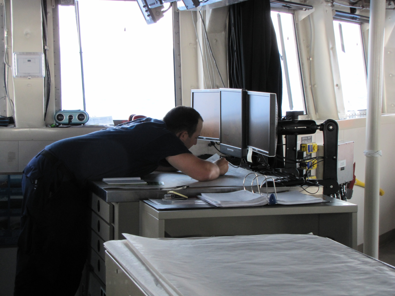 Although electronic charts are used, the officer of the deck is maintaining  aseparate paper chart plot of navigation