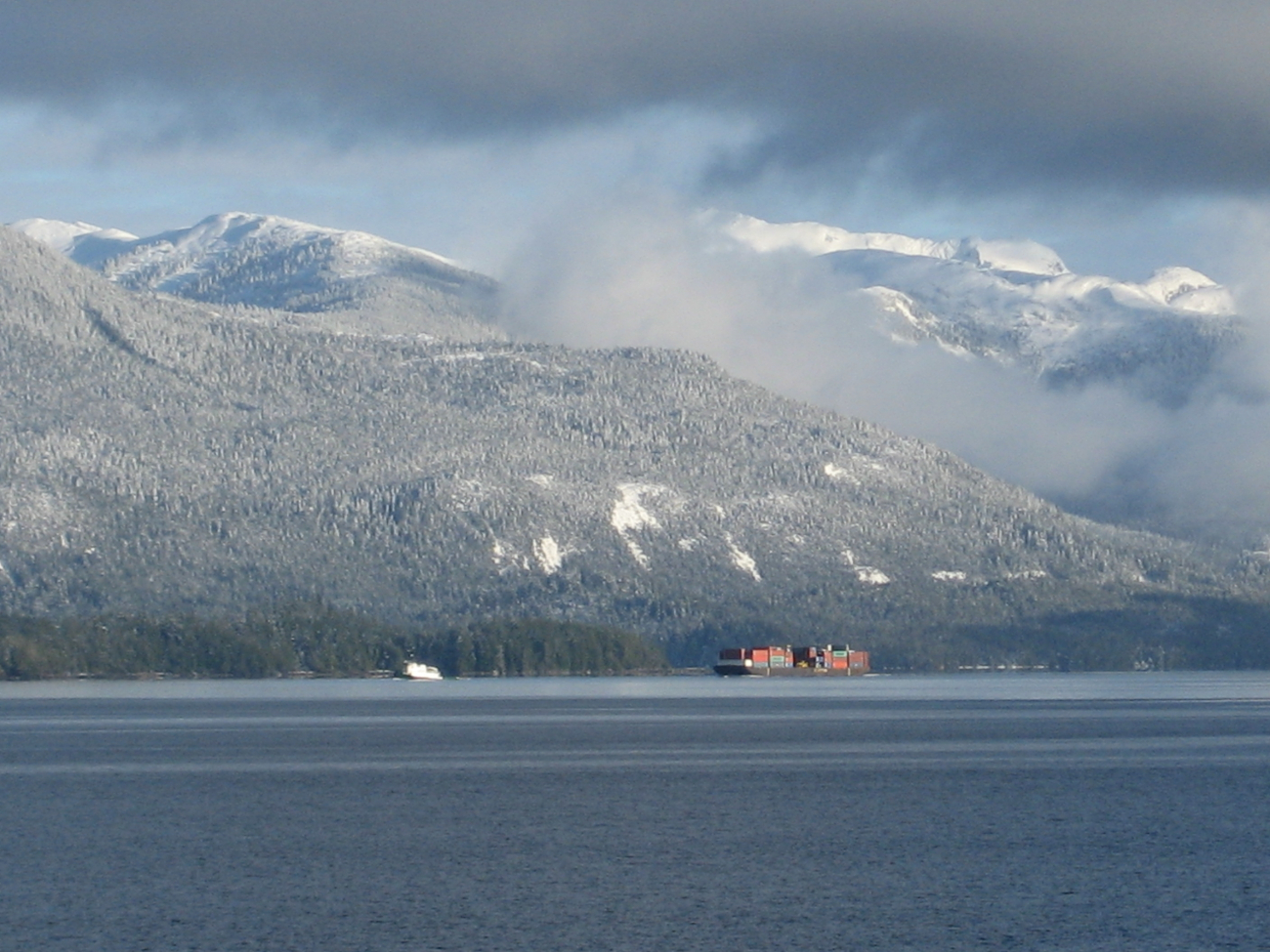 Tug and barge in the Inside Passage after a dusting of snow on the mountains