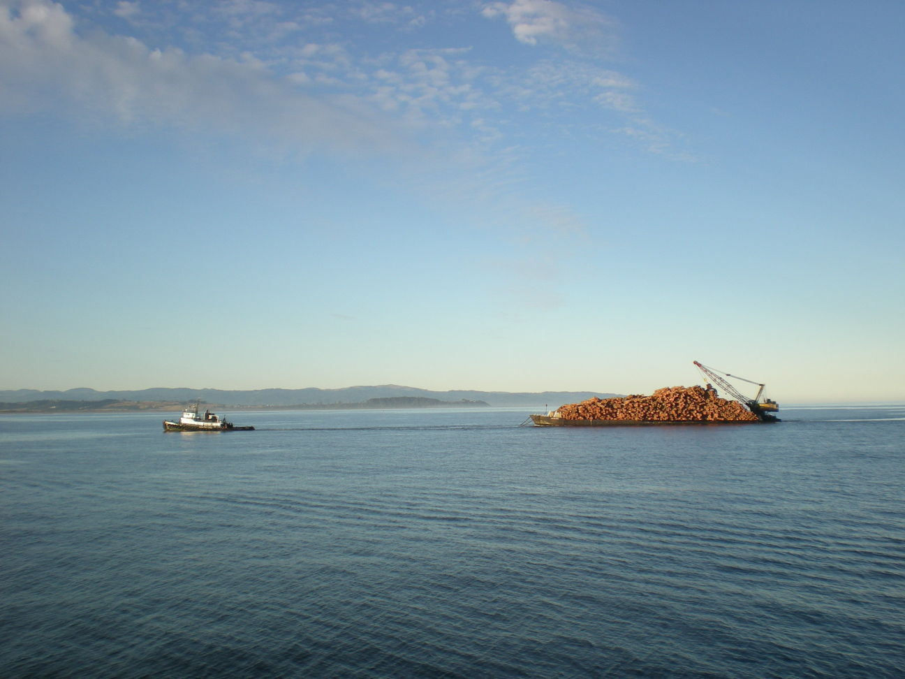 A tug towing a barge-load of logs somewhere in the Inside Passage