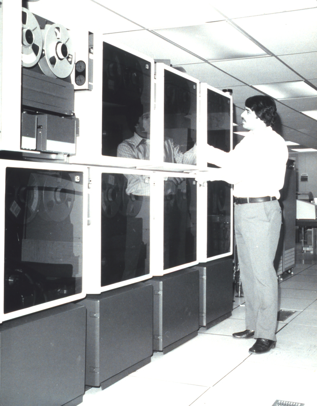 Scientist Frank Porto at the tape drives of the then new National EnvironmentalSatellite Service (NESS) mass data storage system, the SDC TBMII