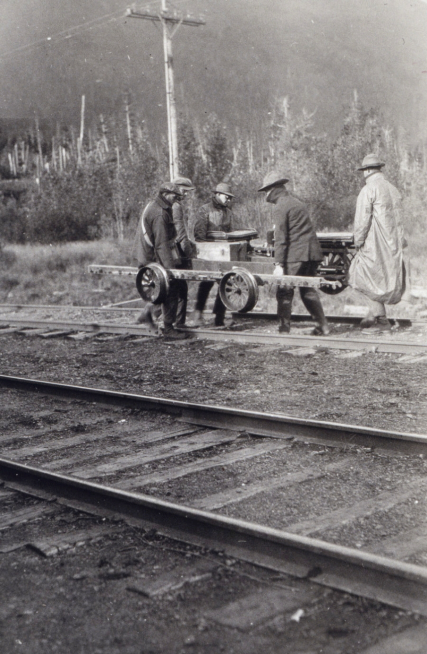 Leveling crew moving velocipede off tracks for approaching train