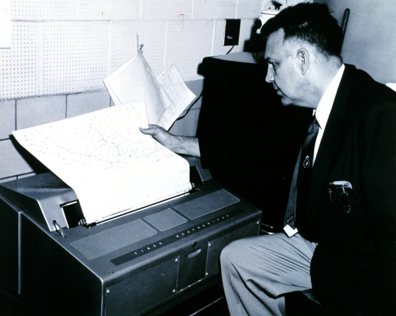 Weather Bureau meteorologist reading a weather map hot off the facscimilemachine