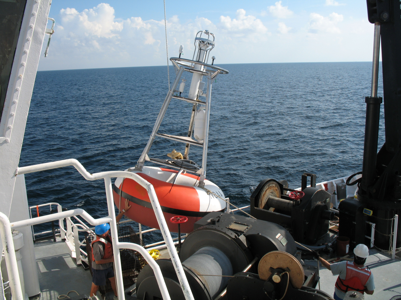 While the clouds approach and the TAO buoy streams aft with attached line,the deck crew of the NOAA Ship GORDON GUNTER move a second TAO toits pre-mooring preparation stand