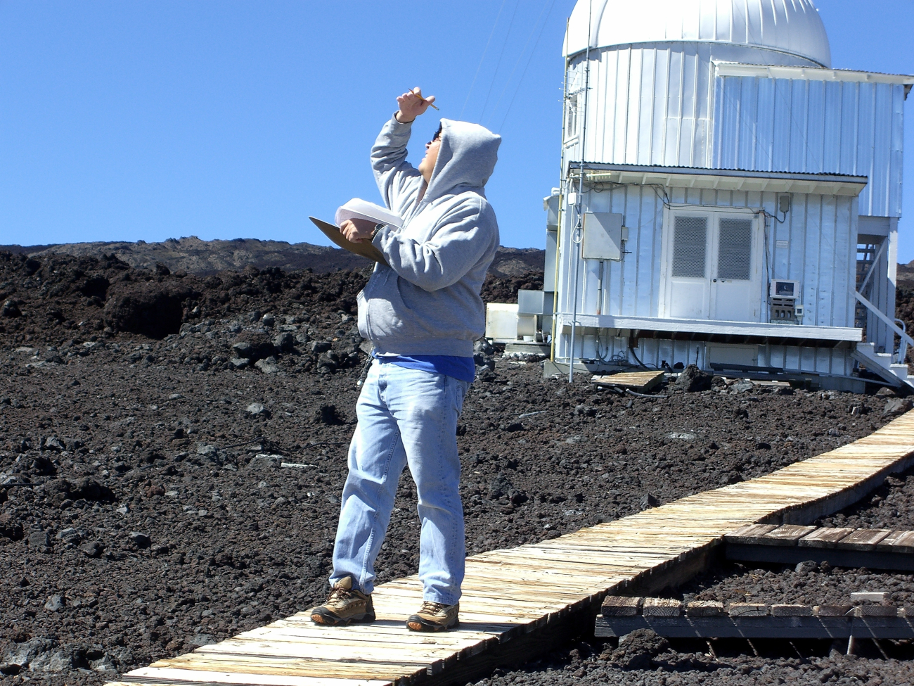 Paul Fukumura-Sawada glances at the sky near the sun to checkfor the presence of aerosols in the sky over NOAA's Mauna Loa Observatory