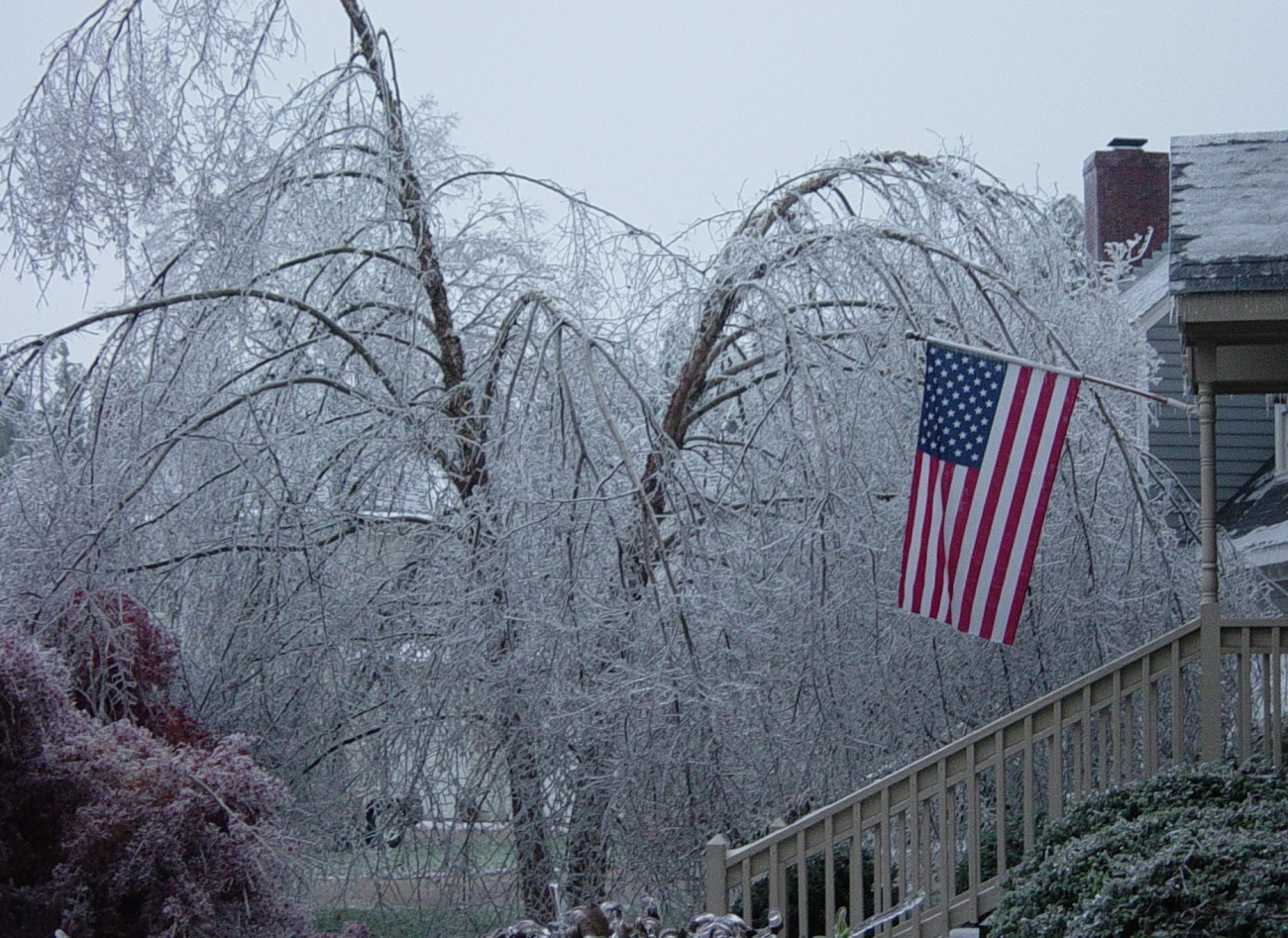 American flag hanging proudly from the porch of a home during a devastating icestorm