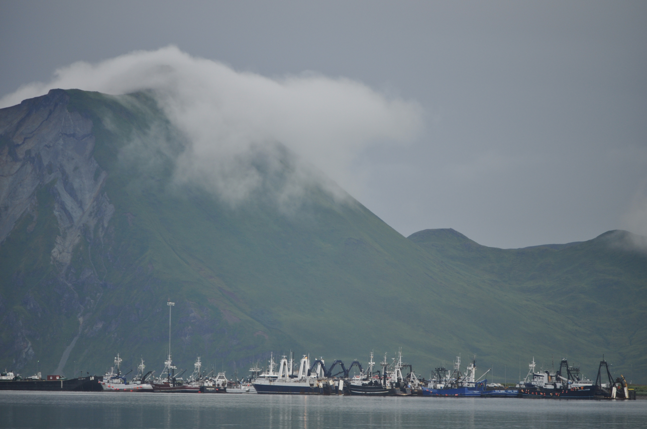 Fog rolling over mountain leaving whispy trail as it invades Dutch Harbor
