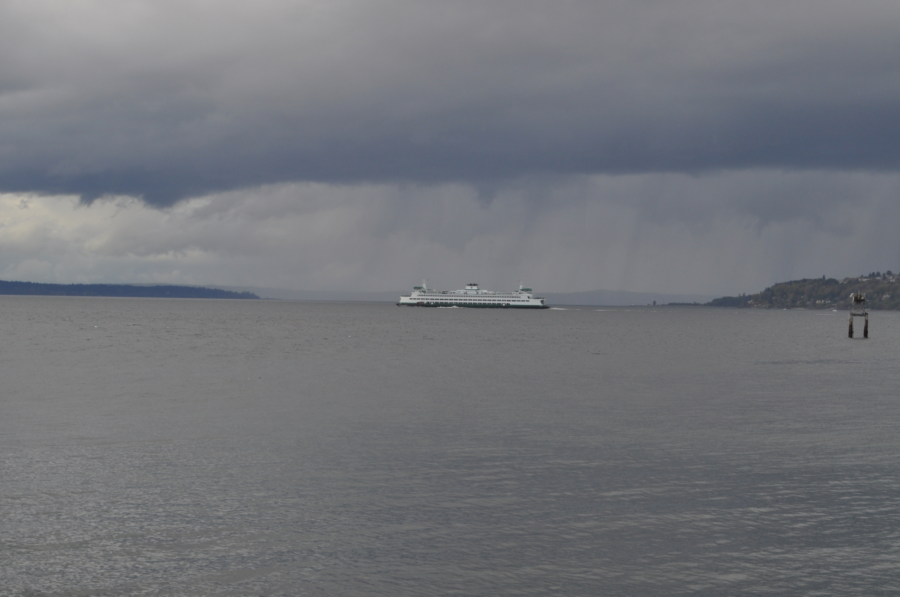 A ferry boat crossing Puget Sound with rain falling in the distance