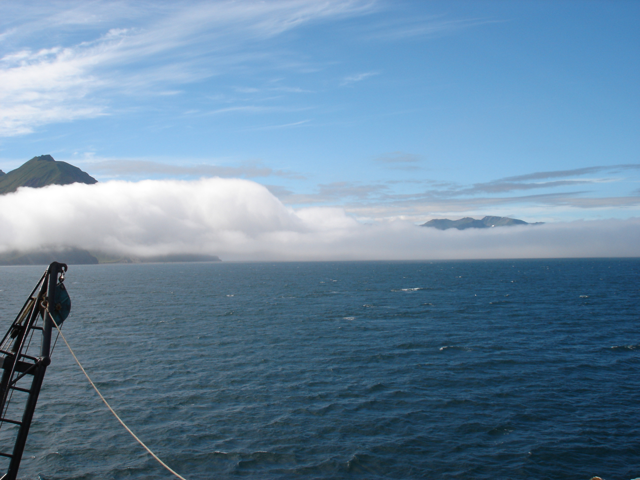 Sun and fog in the Aleutians with high peaks showing above the fog