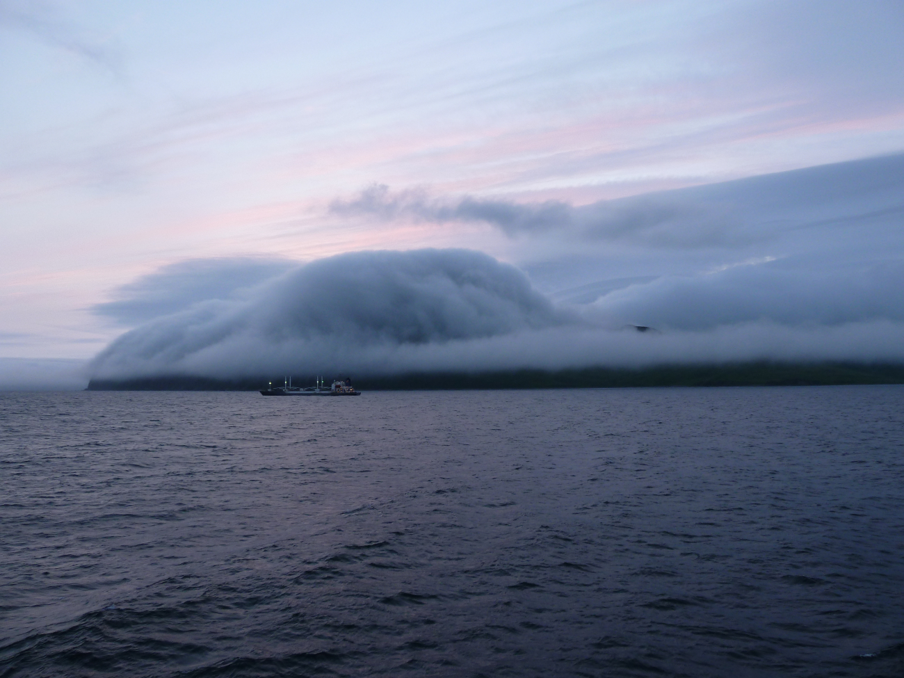 A gentle fog following topography at Dutch Harbor as a freighter leaves for anunknown port