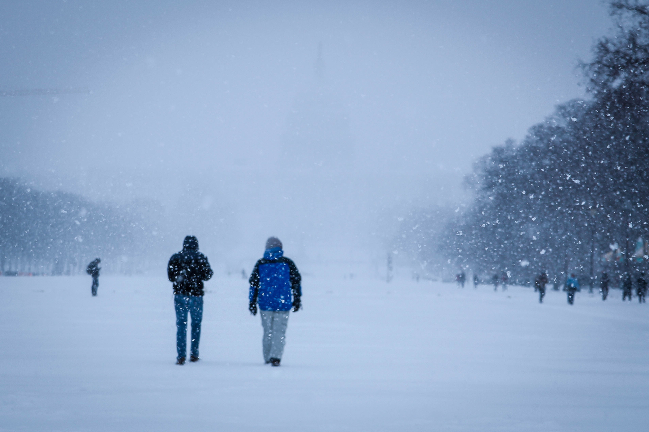 A vague outline of the Capitol Building can be seen through falling snowlooking east on the National Mall