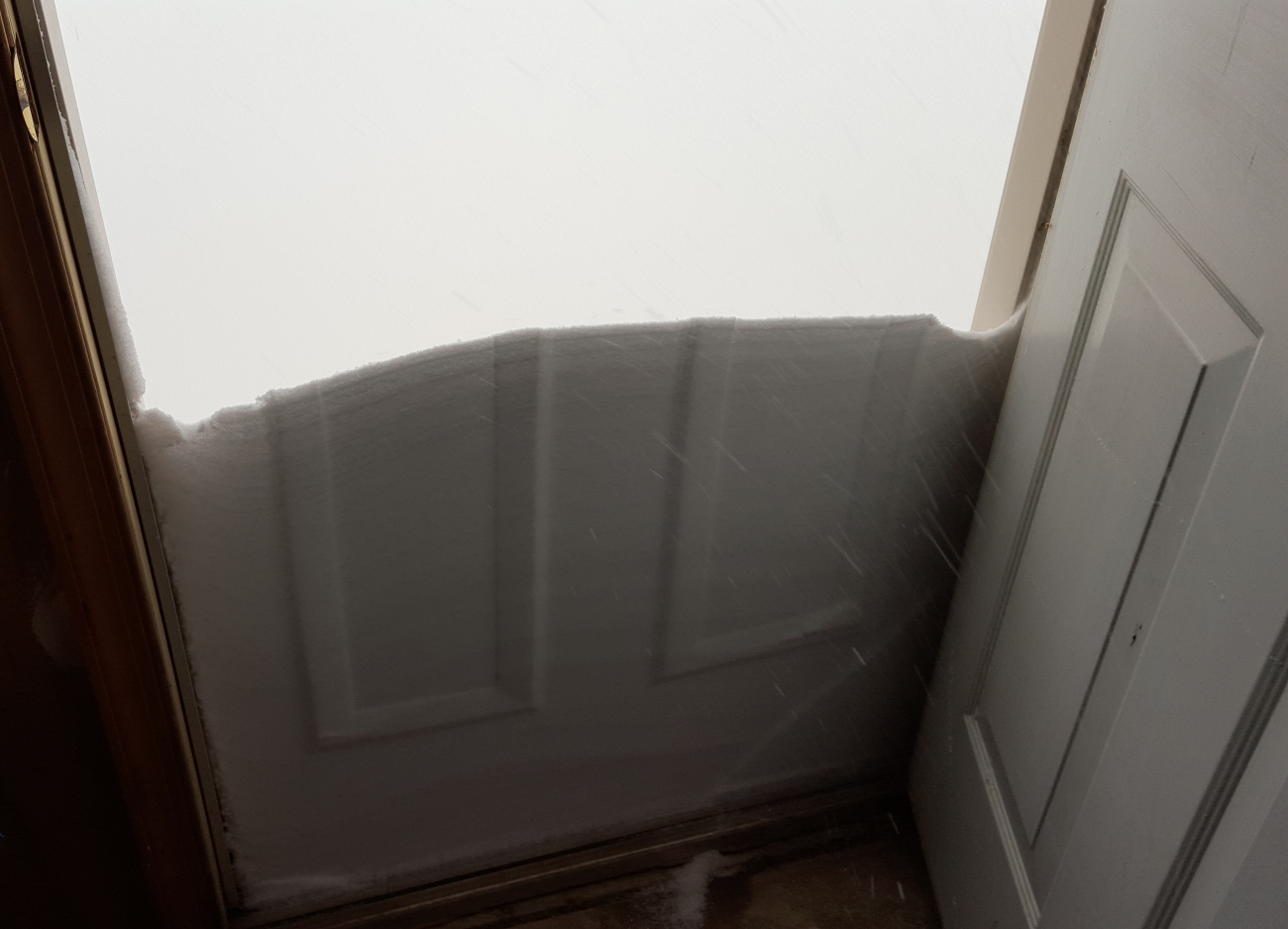 Snow drifted against the front door molded by the pattern on the door