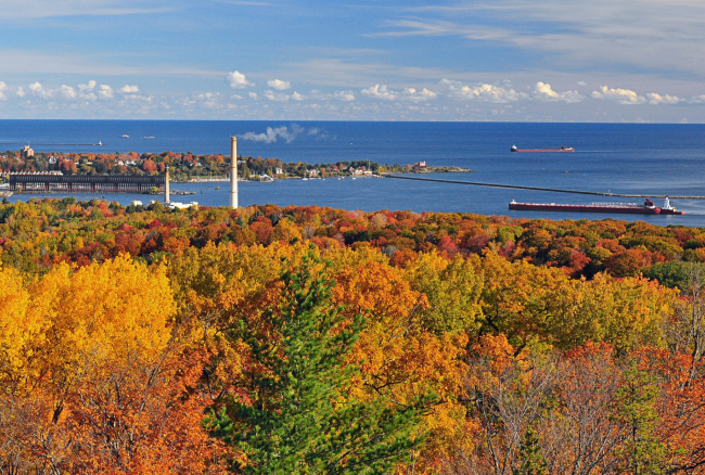 Two large lake bulk carriers arriving at Marquette Harbor with fall foliage inthe foreground