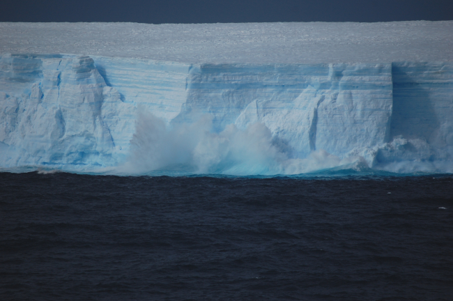 A wave crashing on a large tabular iceberg