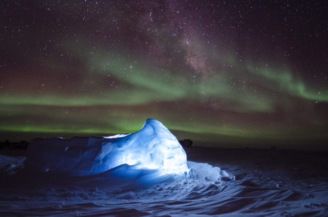 Aurora australis over illuminated ice shelter
