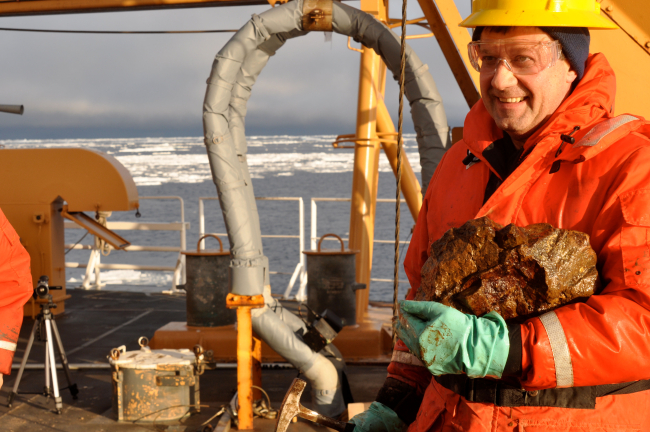 Scientist with rock hammer and specimen of rock from bottom of Beaufort Sea
