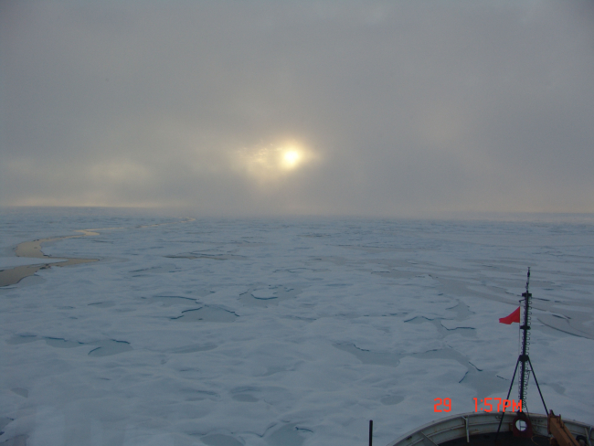 Sun peaking through the clouds while the HEALY plows through ice floes andmelt ponds
