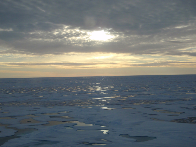 Sun seen through the clouds over a vast ice field