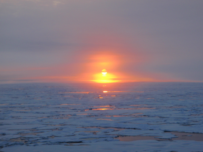 Sun reflecting off open water between ice floes