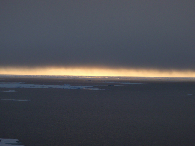 In a polynya looking towards sunlight playing on water while a blanket of cloudtotally obscures the sun