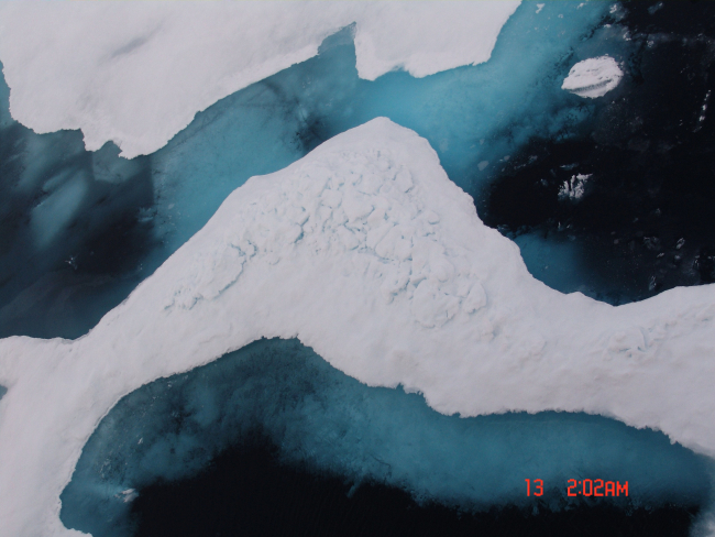 Deteriorating ice floes with melt pools, blue-green ice, and deep dark water inlate summer