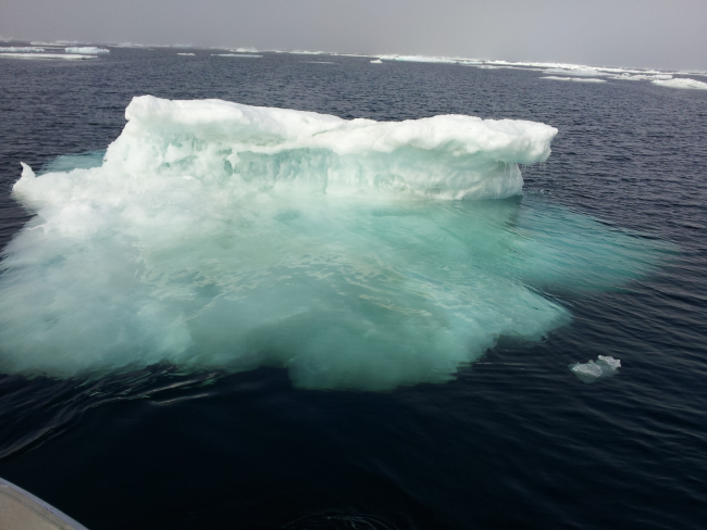 A small ice berg with its greater mass of ice visible below the surface