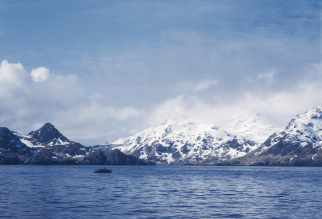 On the working grounds, a survey launch is dwarfed by the volcanic shores of theAleutian Islands