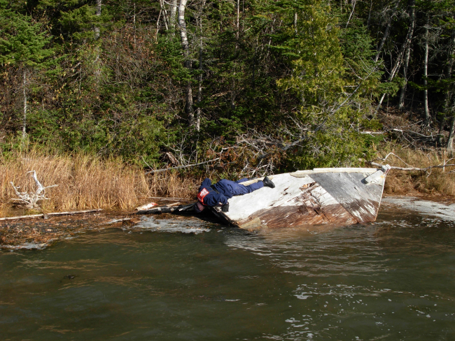 Coast Guardsman checking sunken vessel prior to recovering as marine debris