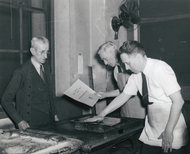 Old-timers checking certificate printed on lithographers stone