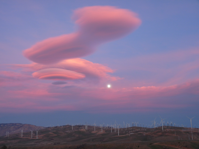 Lenticular clouds with the rising winter Snow Moon above a sea of windturbines