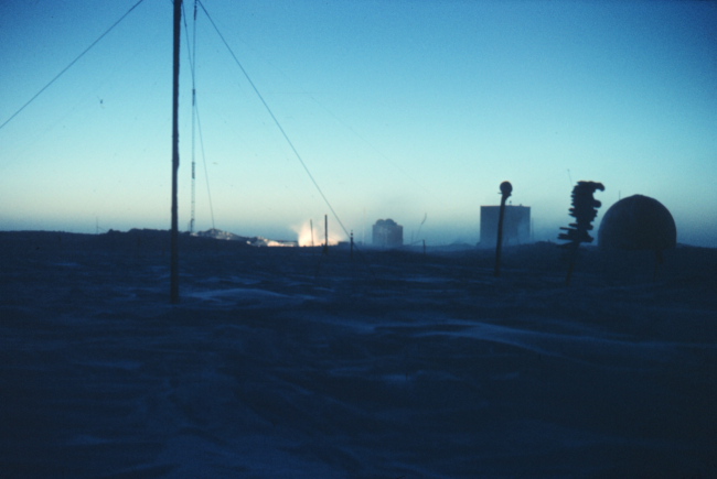 The first sunrays illuminating the generator exhaust at South Pole Station