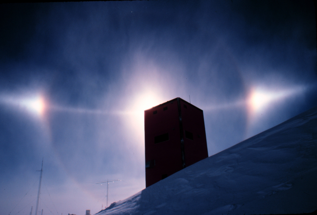 Small halo, sun dogs, and arc of much larger halo nearly bisecting smaller halo