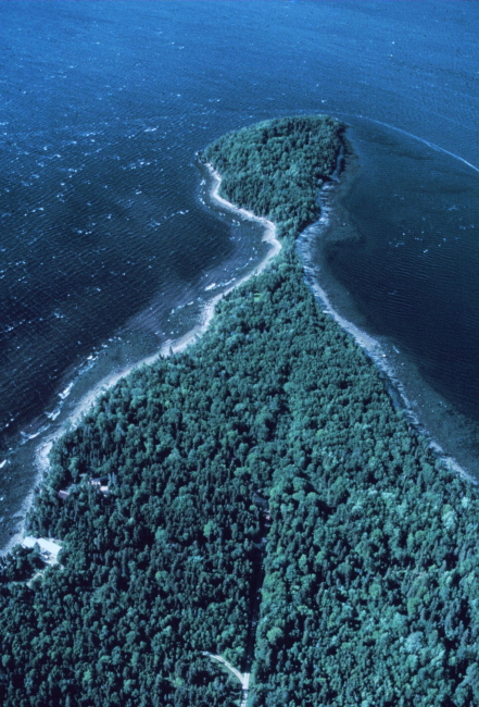 Apparently a tree-covered  peninsula with a rocky shoreline